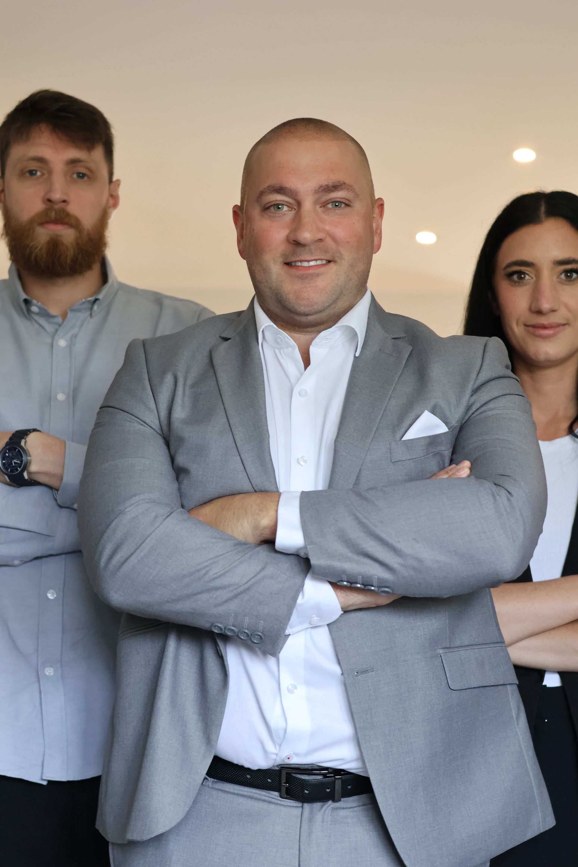 three people are posing for a picture with their arms crossed .