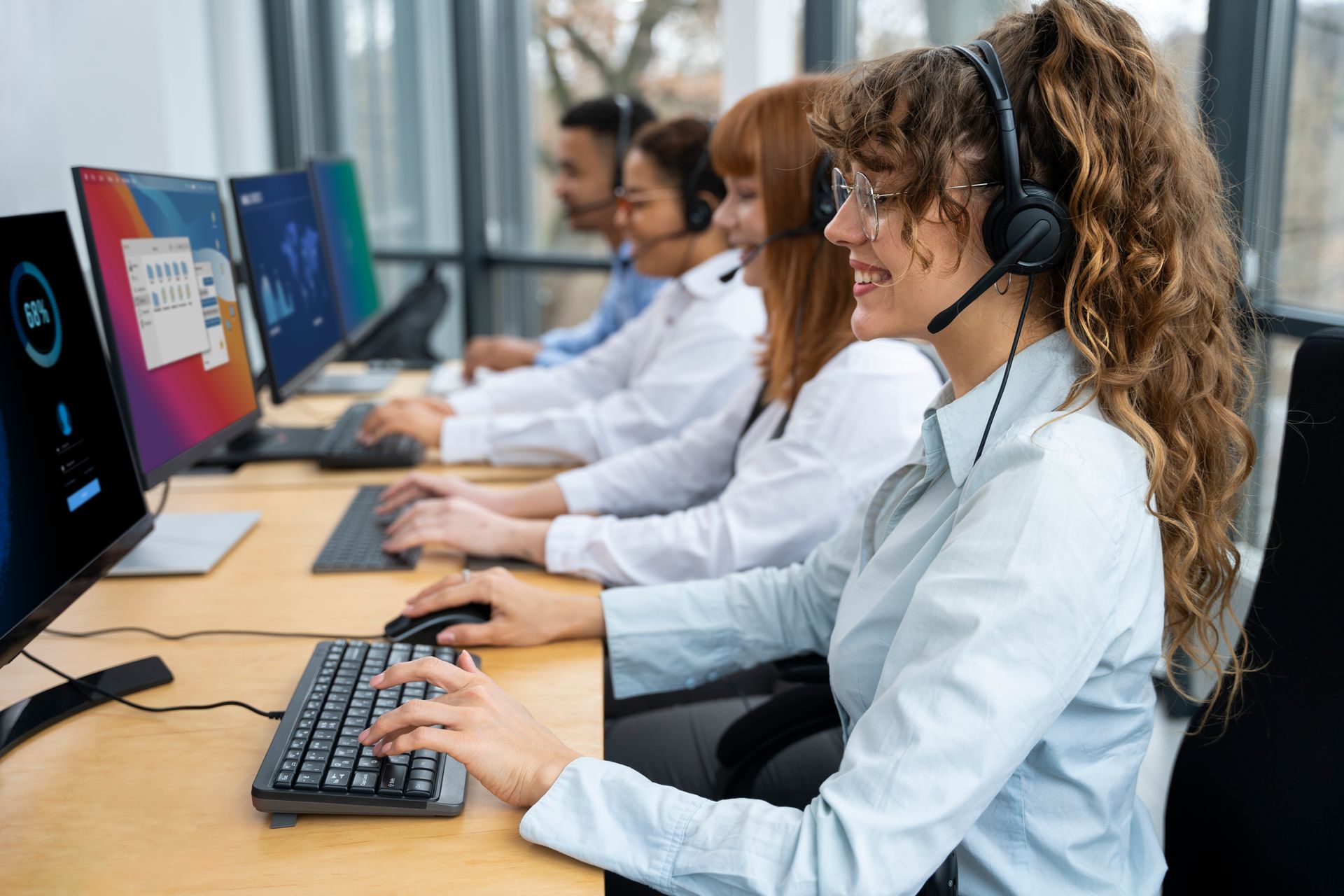 a woman wearing a headset is sitting at a desk in front of a computer .