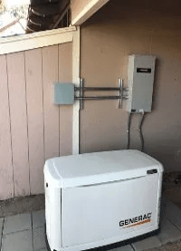 A generator is sitting on top of a concrete platform in front of a building.