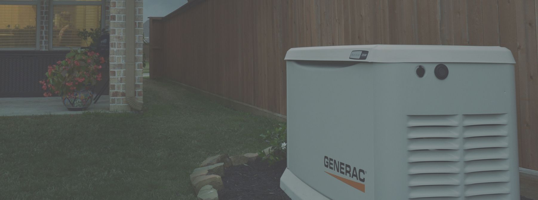 A generator is sitting in the backyard of a house next to a wooden fence.