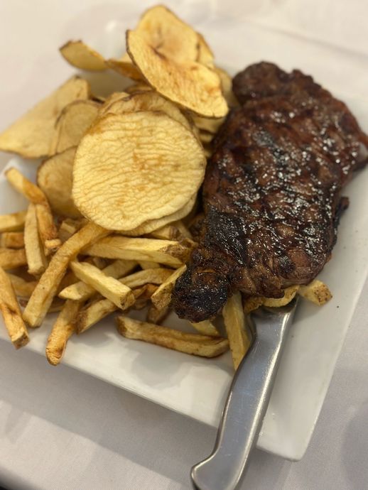 A white plate topped with a steak and french fries.