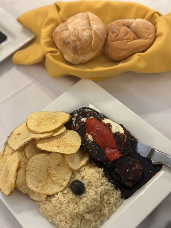 A plate of food with rice , potato chips , and bread on a table.