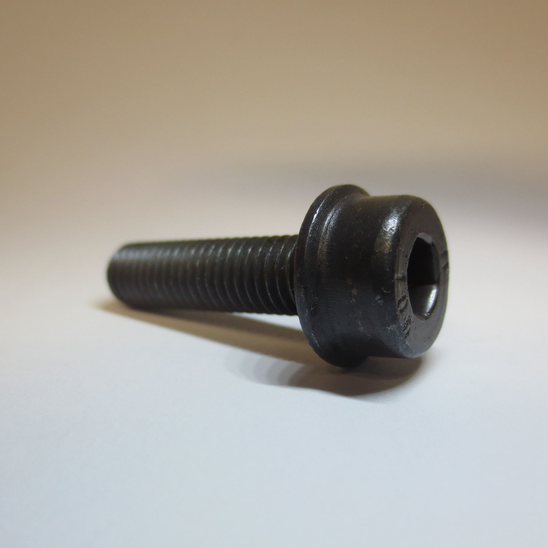 Eine Nahaufnahme einer schwarzen Schraube auf einer weißen Oberfläche