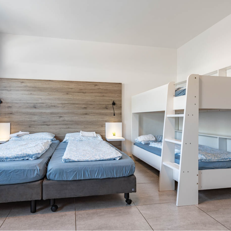 A bright, white bedroom with two twin beds and a bunk bed.