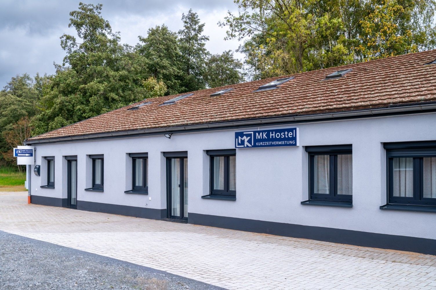 White building with brown tile roof, black-framed windows, sign reading 