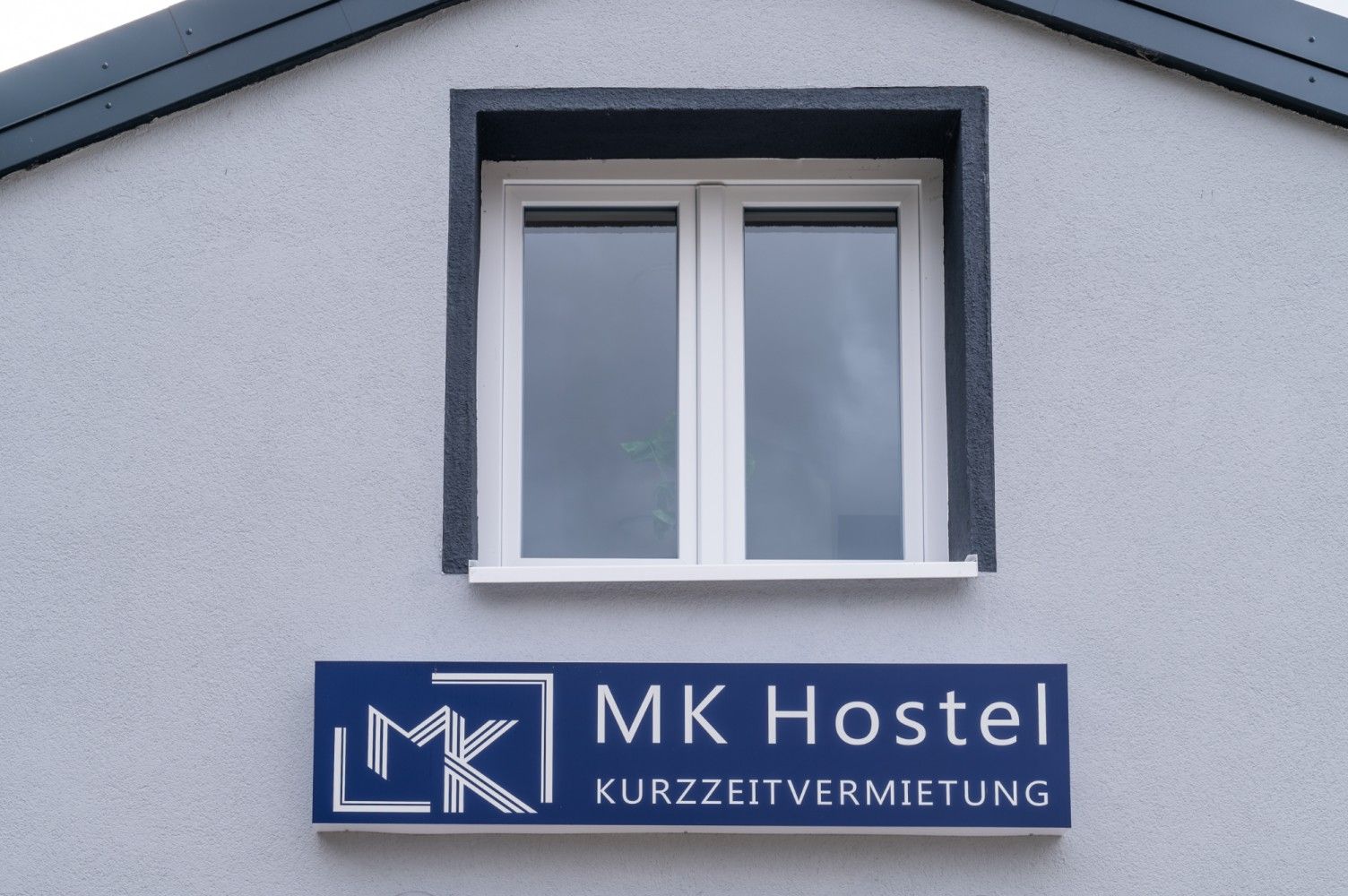 Window on gray building, sign reads 