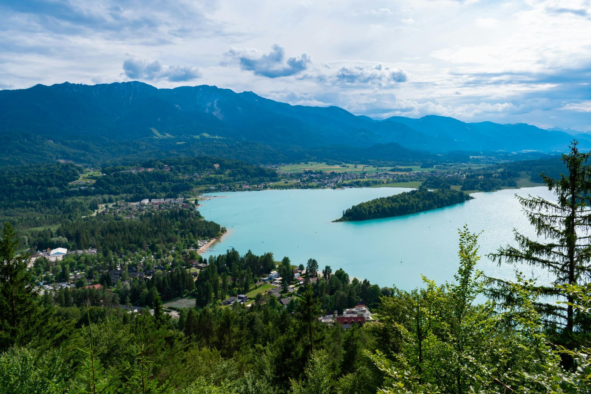 Lake Bled, Slovenia: Turquoise lake surrounded by forested hills and mountains, under a cloudy sky.