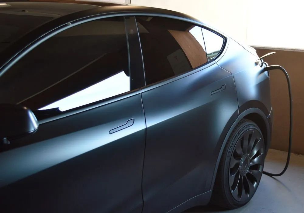 Dark gray Tesla Model Y plugged in for charging.