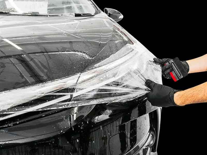 Close-up of a car hood with professionally applied paint protection film, showcasing its glossy finish and protective benefits.
