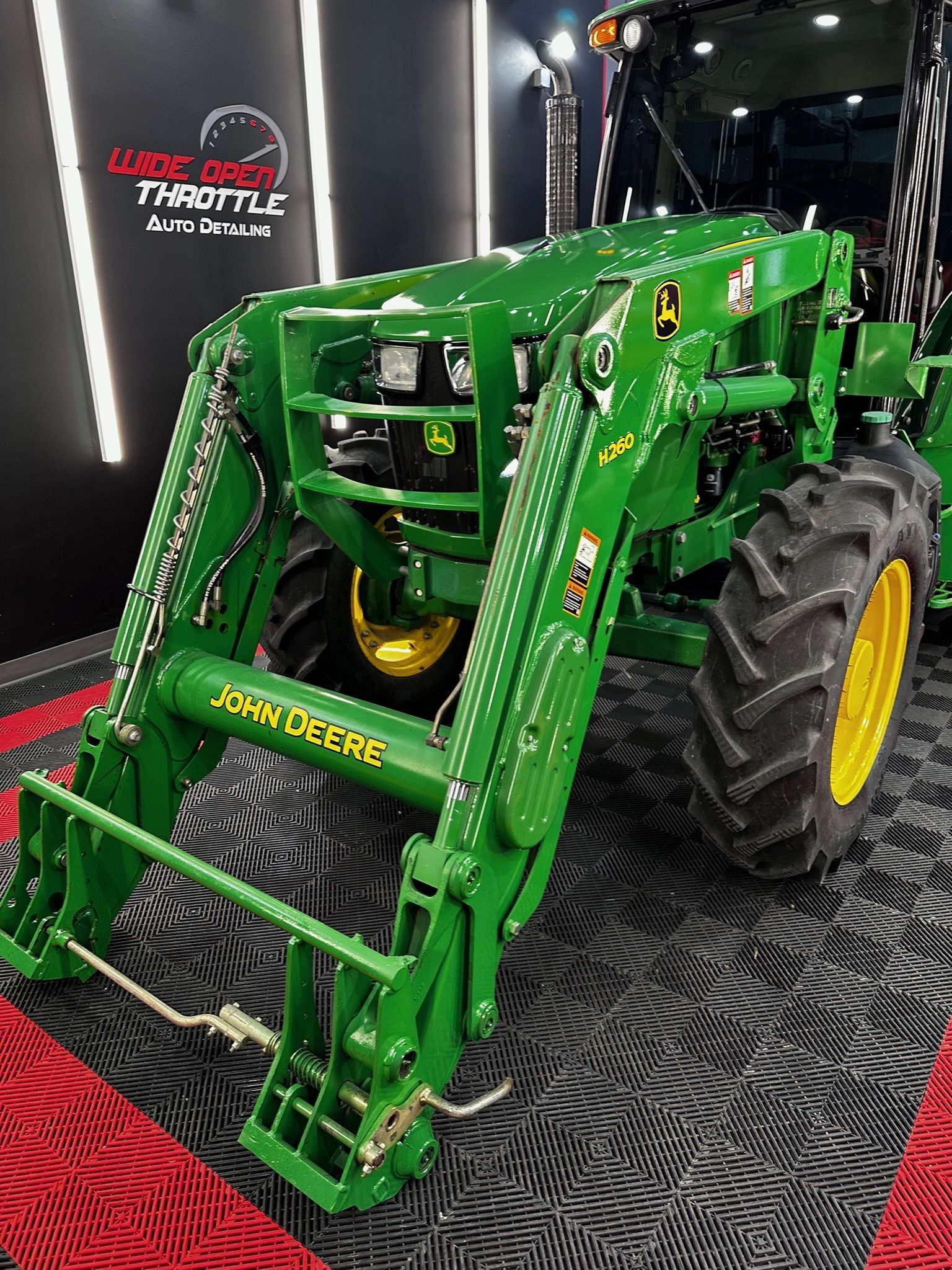 Green John Deere tractor with front loader; yellow tires.