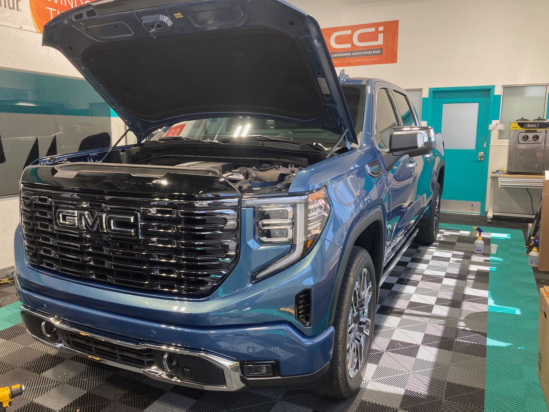 Blue GMC truck with open hood in a shop.