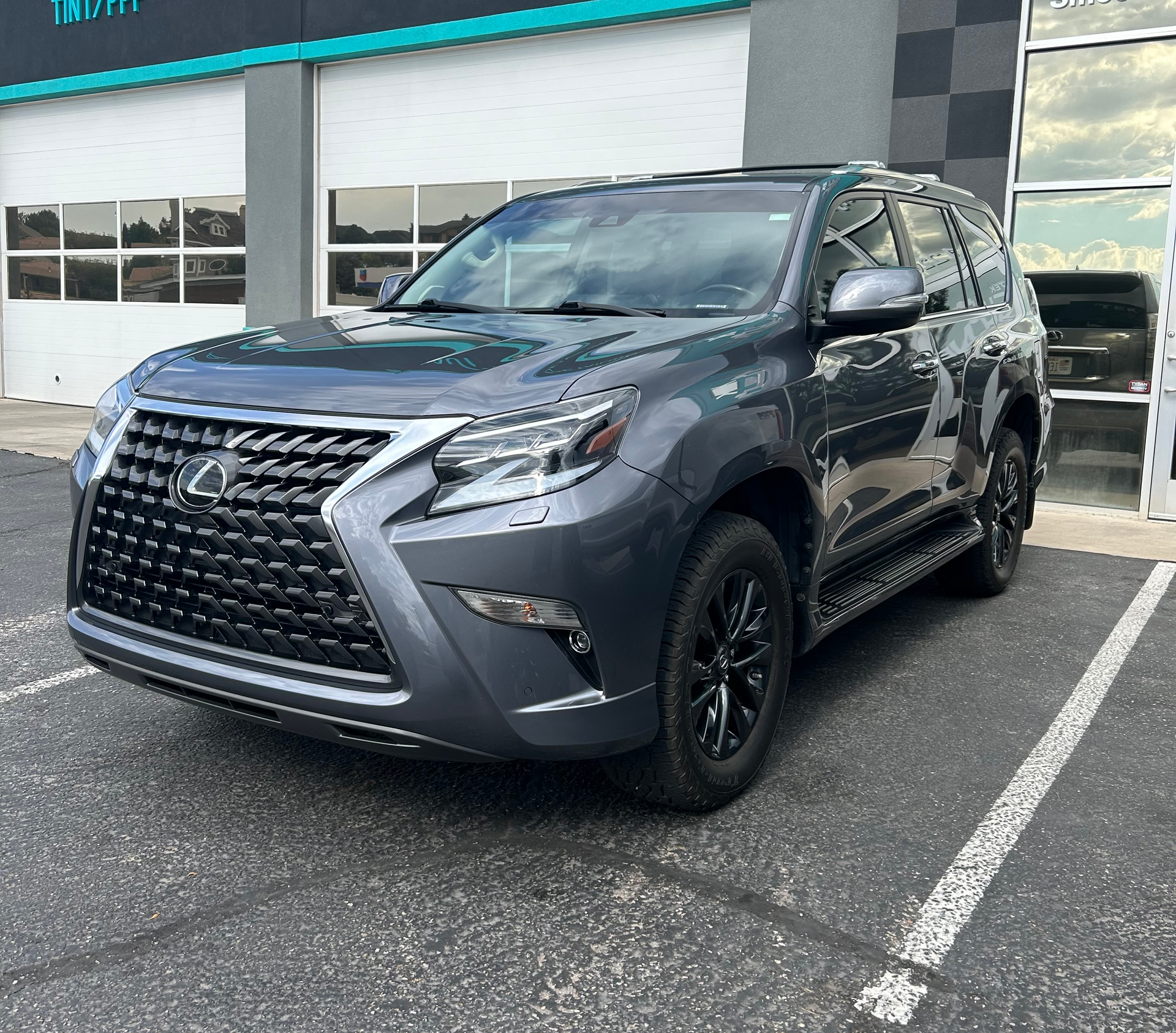 Black Tesla parked in front of a turquoise Tek Shine building with black trim.