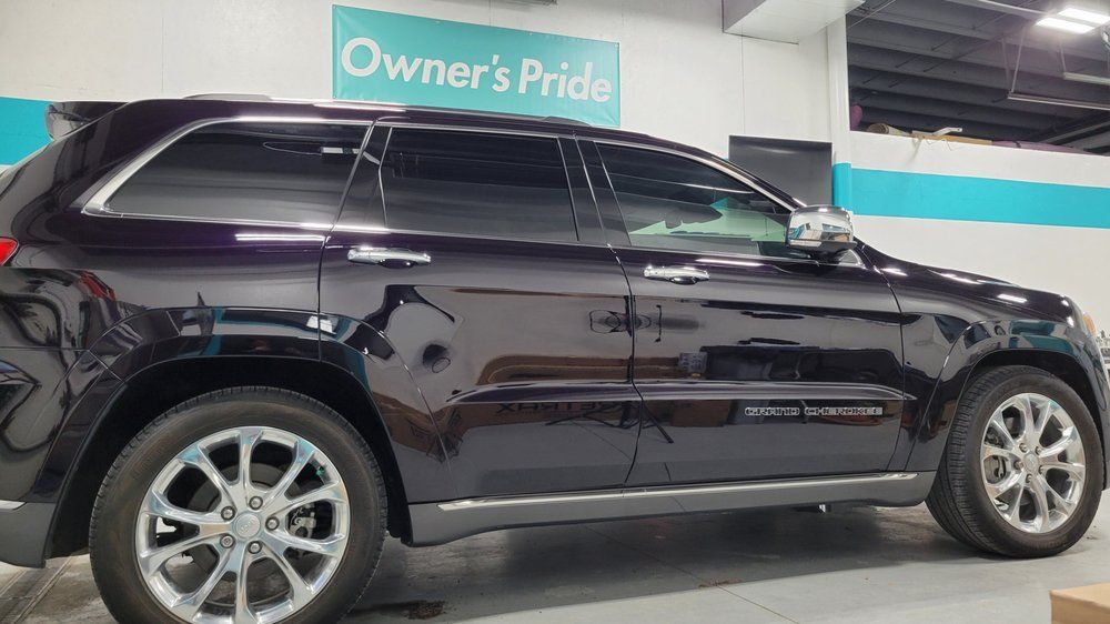 Dark purple Jeep Grand Cherokee with tinted windows in a garage, next to