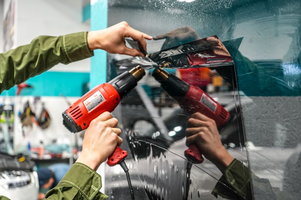 Black GMC truck hood being covered in protective film by a person's hands.
