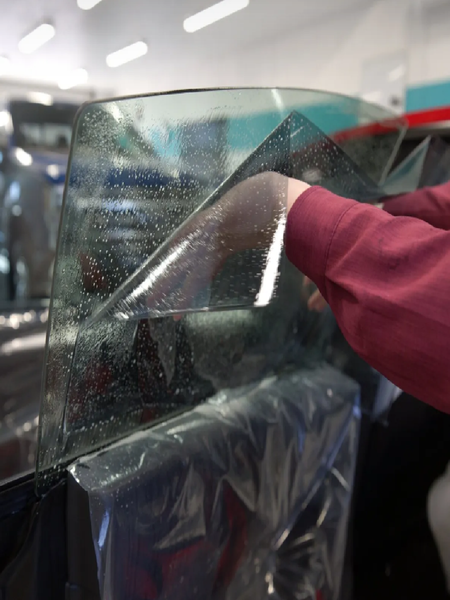 Smoothing out window tint film on a car door with water solution.