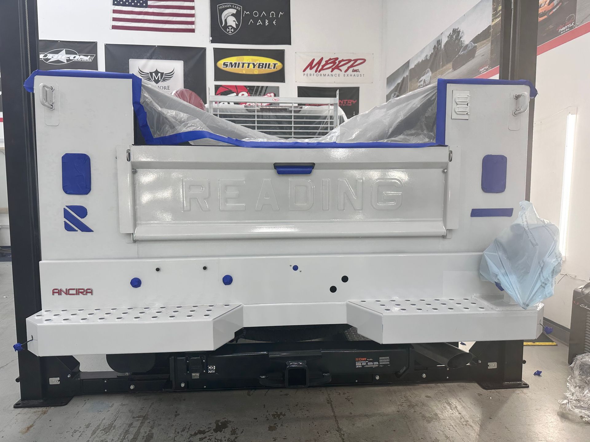 A white truck is being painted in a garage.