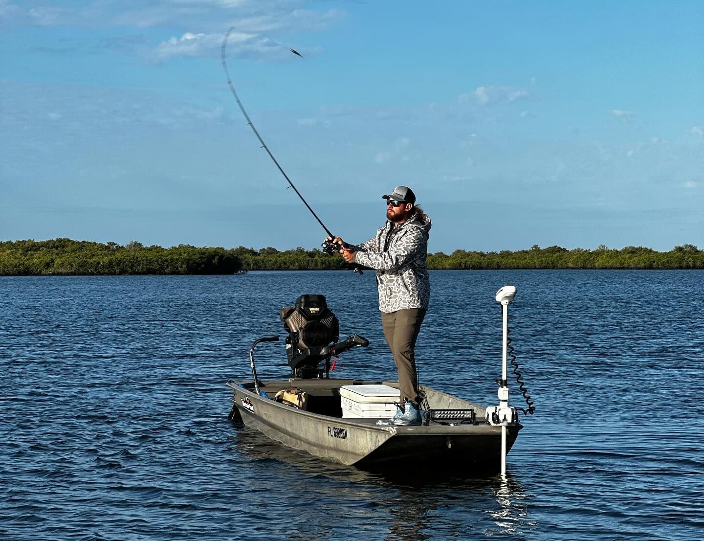 A man is fishing from a boat on a lake.