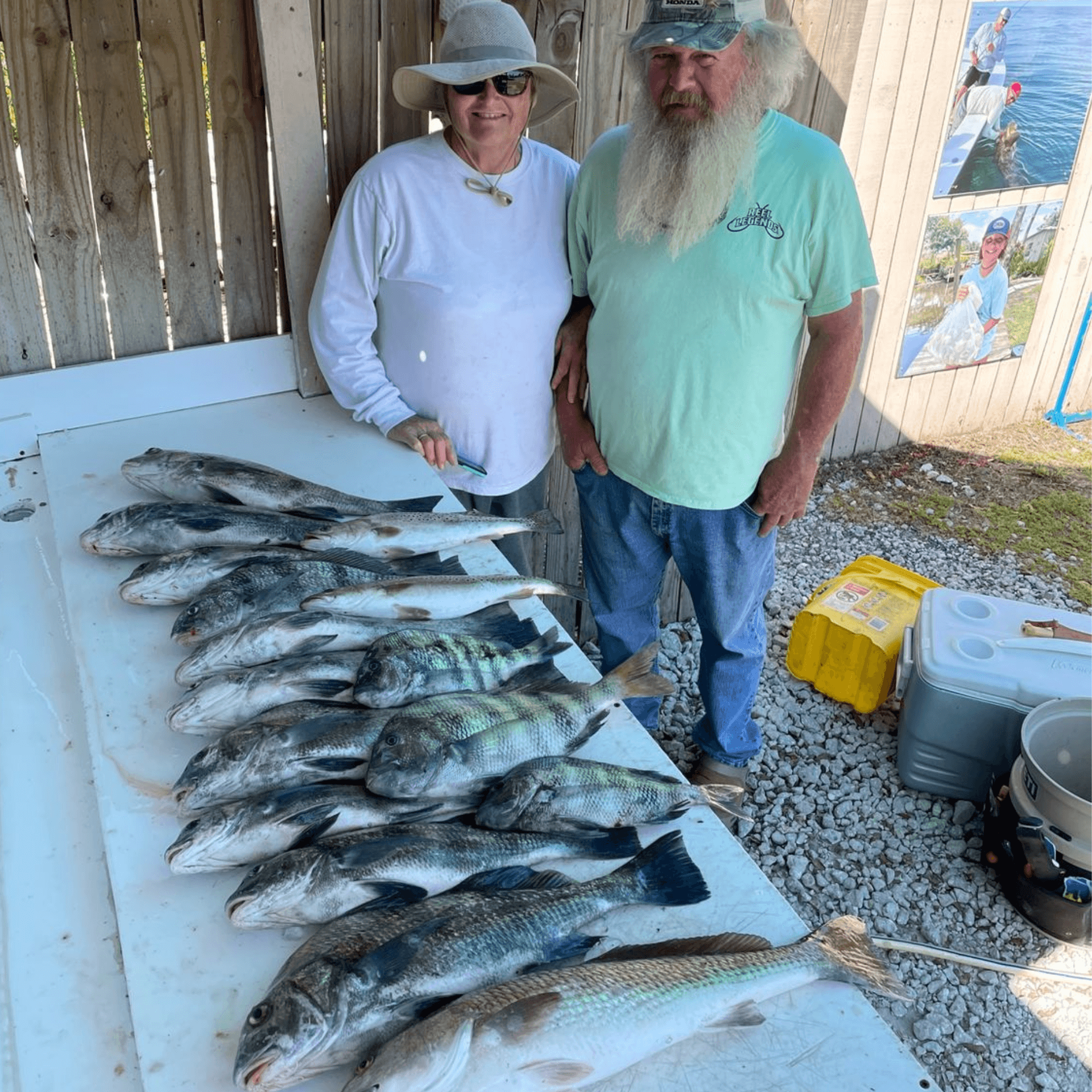 A man and a woman are standing next to a table full of fish.