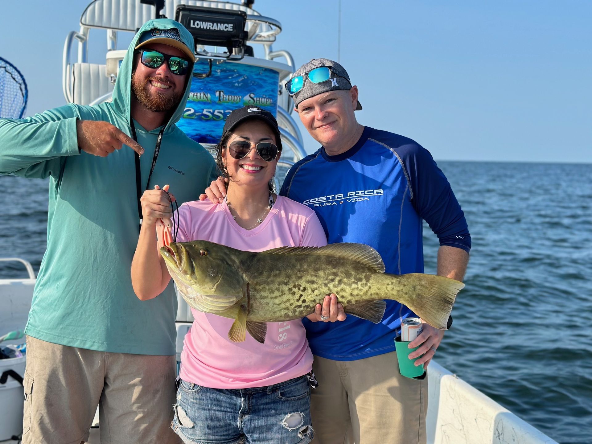 A group of people are standing on a boat holding a large fish.