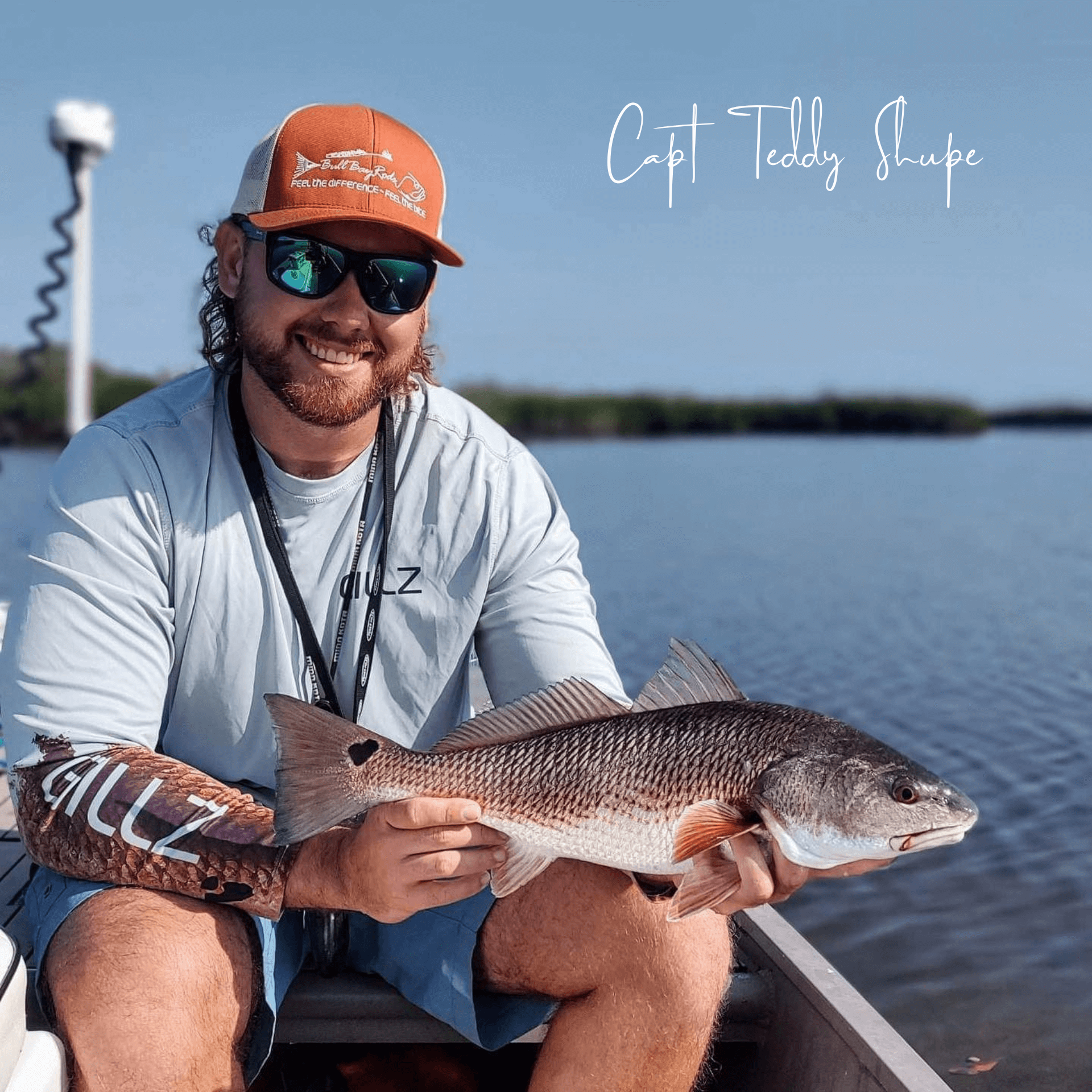 Capt Teddy Shupe is sitting in a boat holding a large Redfish.