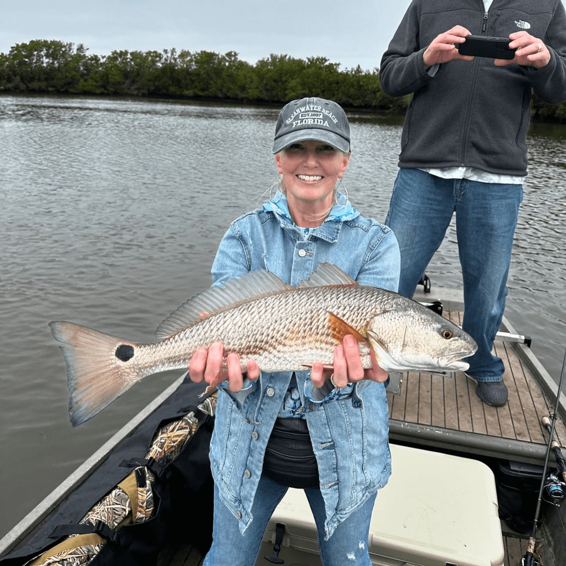 A woman is holding a large fish in her hands on a boat.