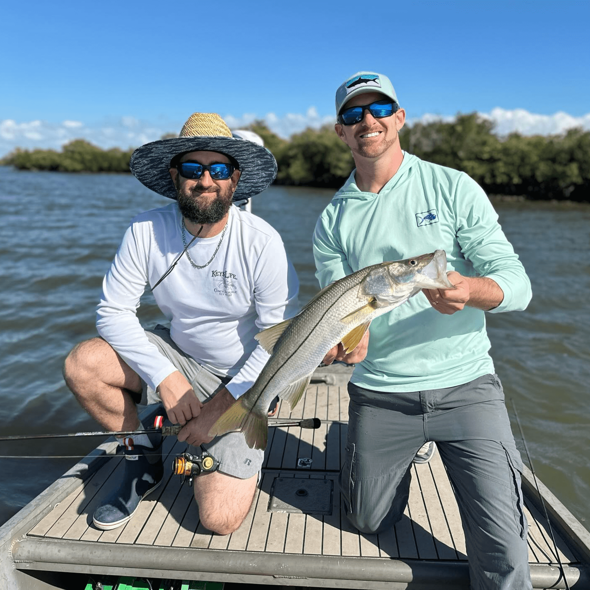 Two men are sitting on a boat holding a fish.