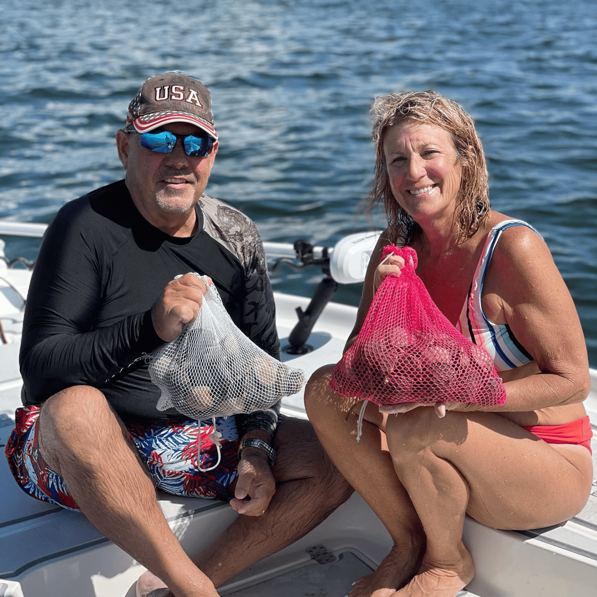 A man and a woman are sitting on a boat holding bags of bay scallops.