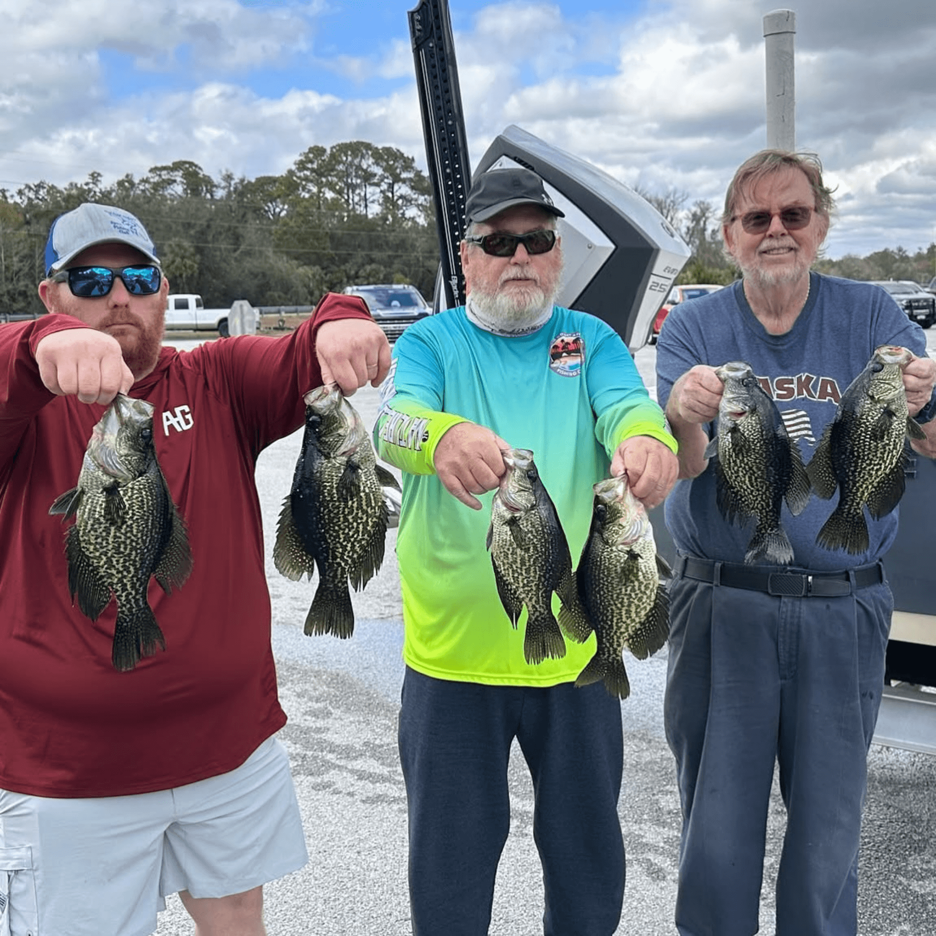 Three men are standing next to each other holding fish in their hands.