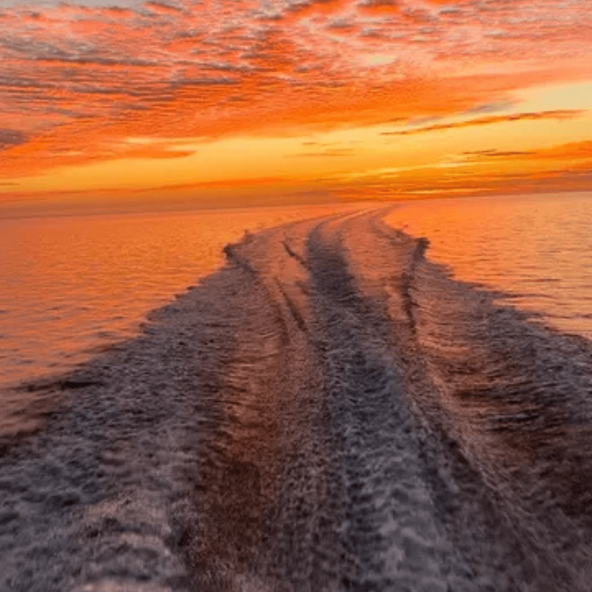 A boat is going through the ocean at sunset.