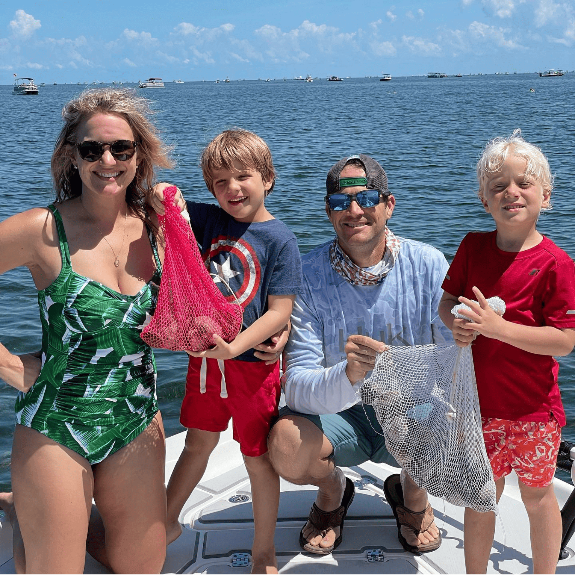 A family is posing for a picture on a boat in the ocean with a scallop harvest
