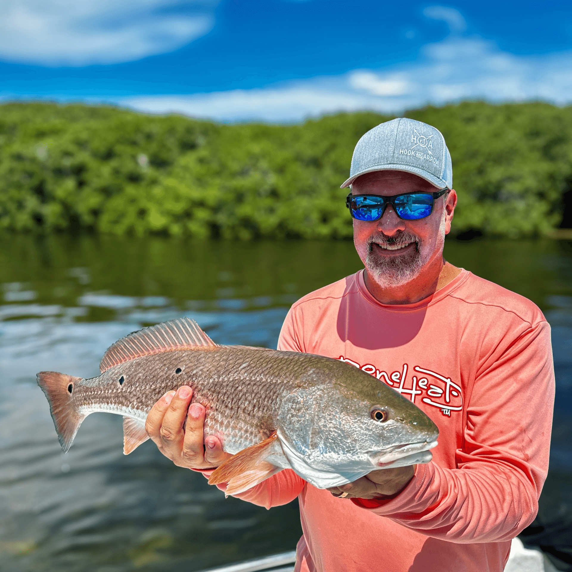 A man is holding a large fish in his hands on a boat.