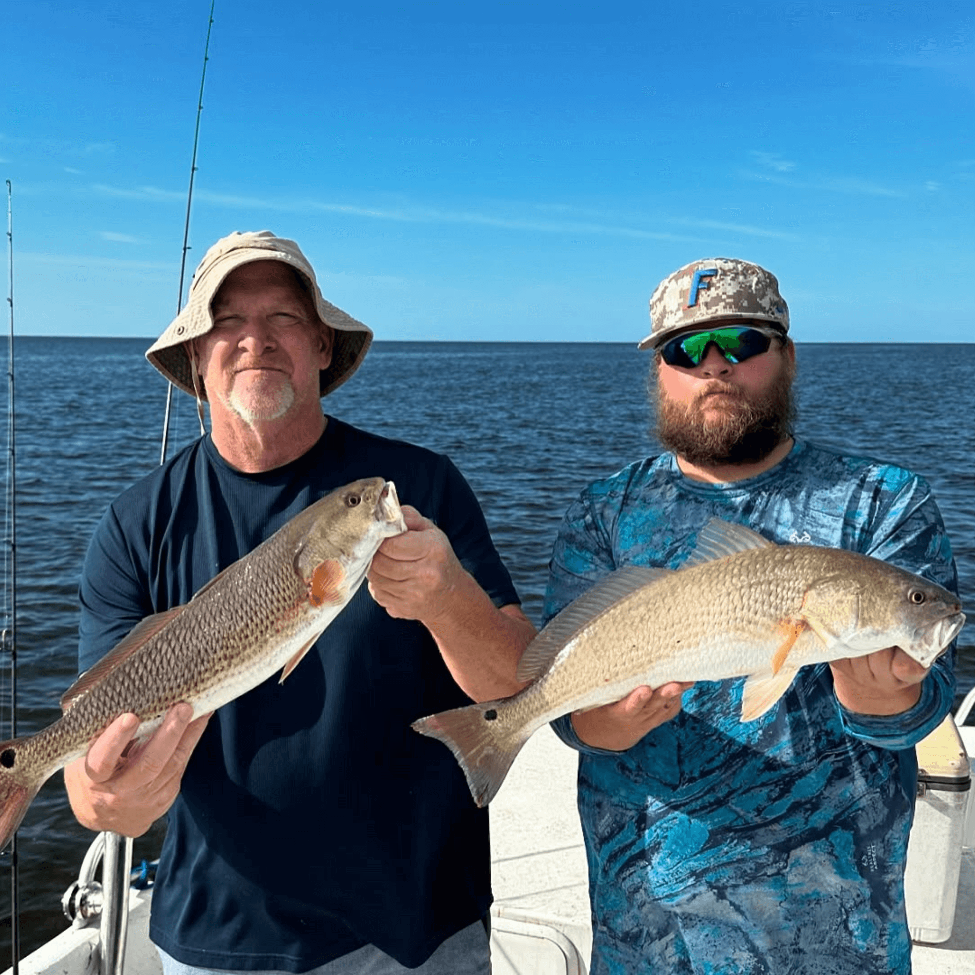 Two men are holding two fish on a boat.