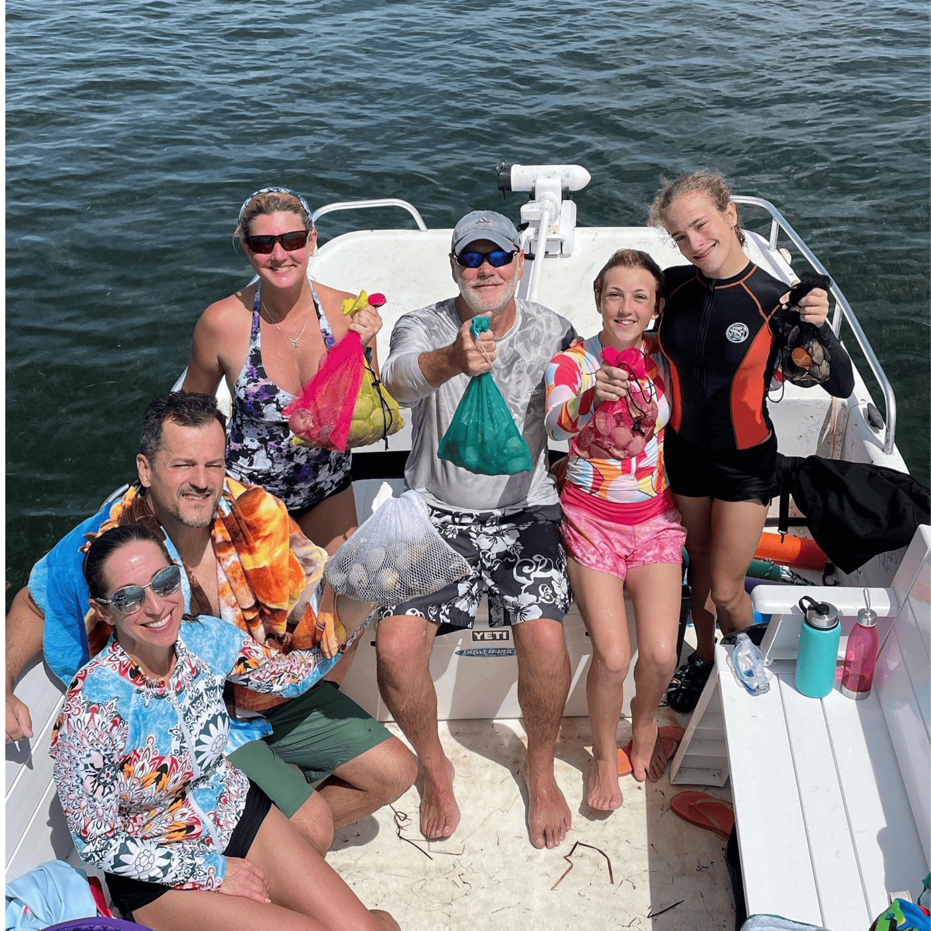 A group of people are posing for a picture on a boat with scallops