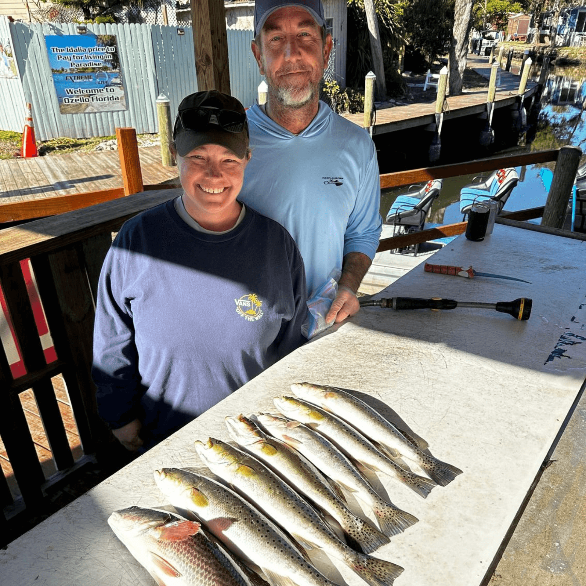 A man and a woman are standing next to a filet table full of fish.