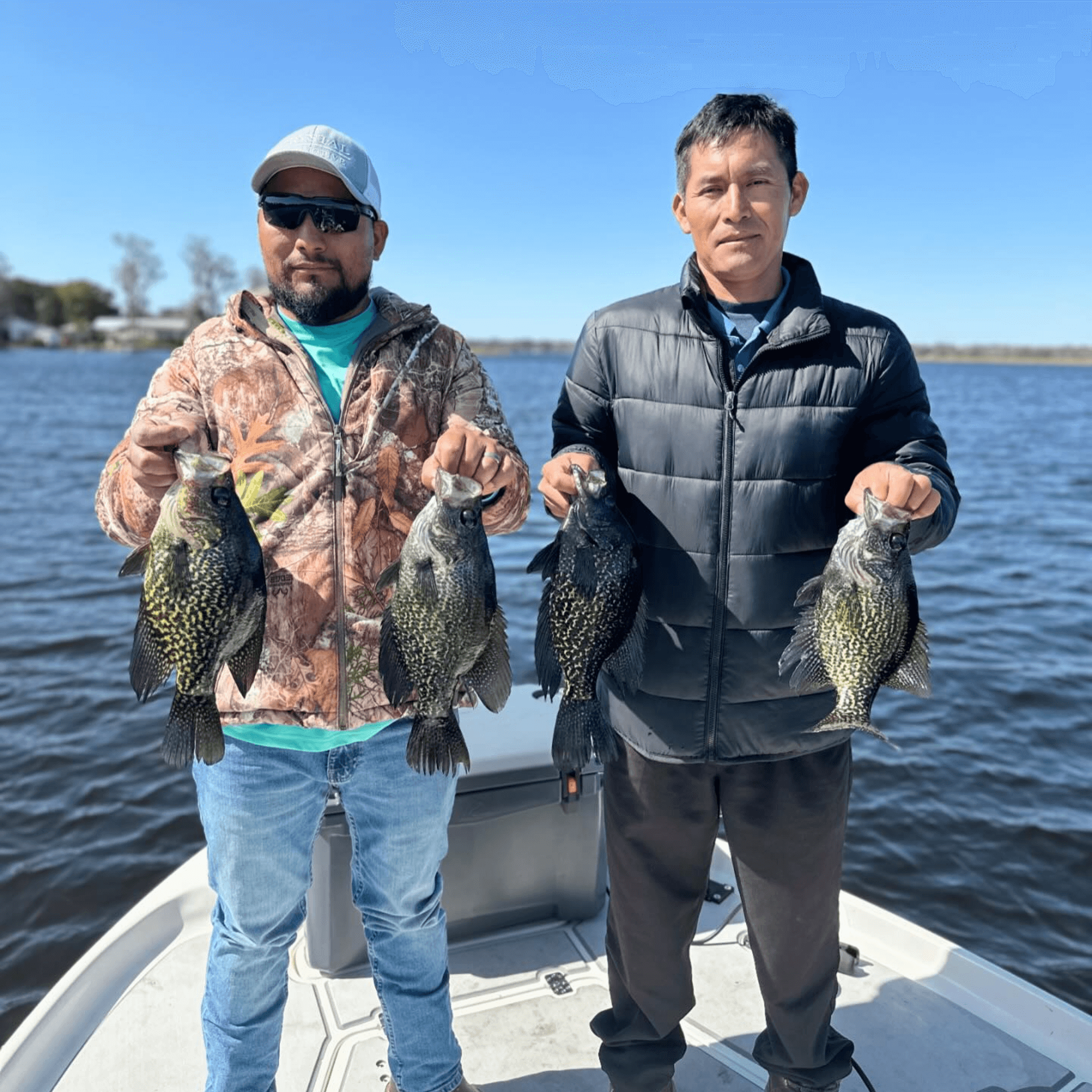 Two men are standing on a boat holding fish in their hands.