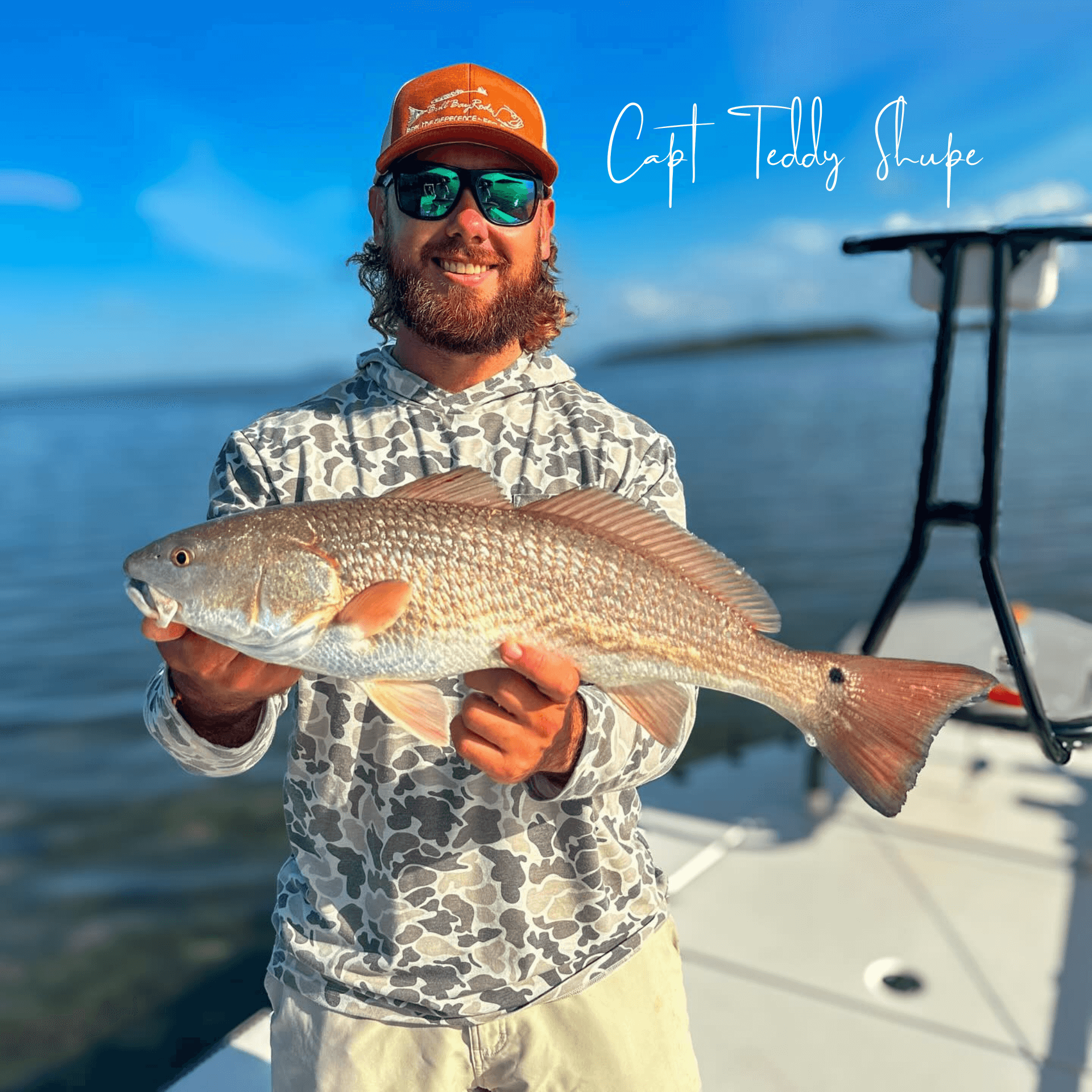 A man is holding a large redfish on a boat.