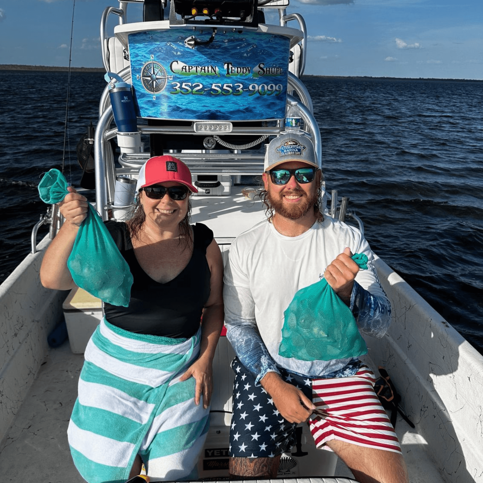 A man and a woman are sitting on a boat holding bags of clams.