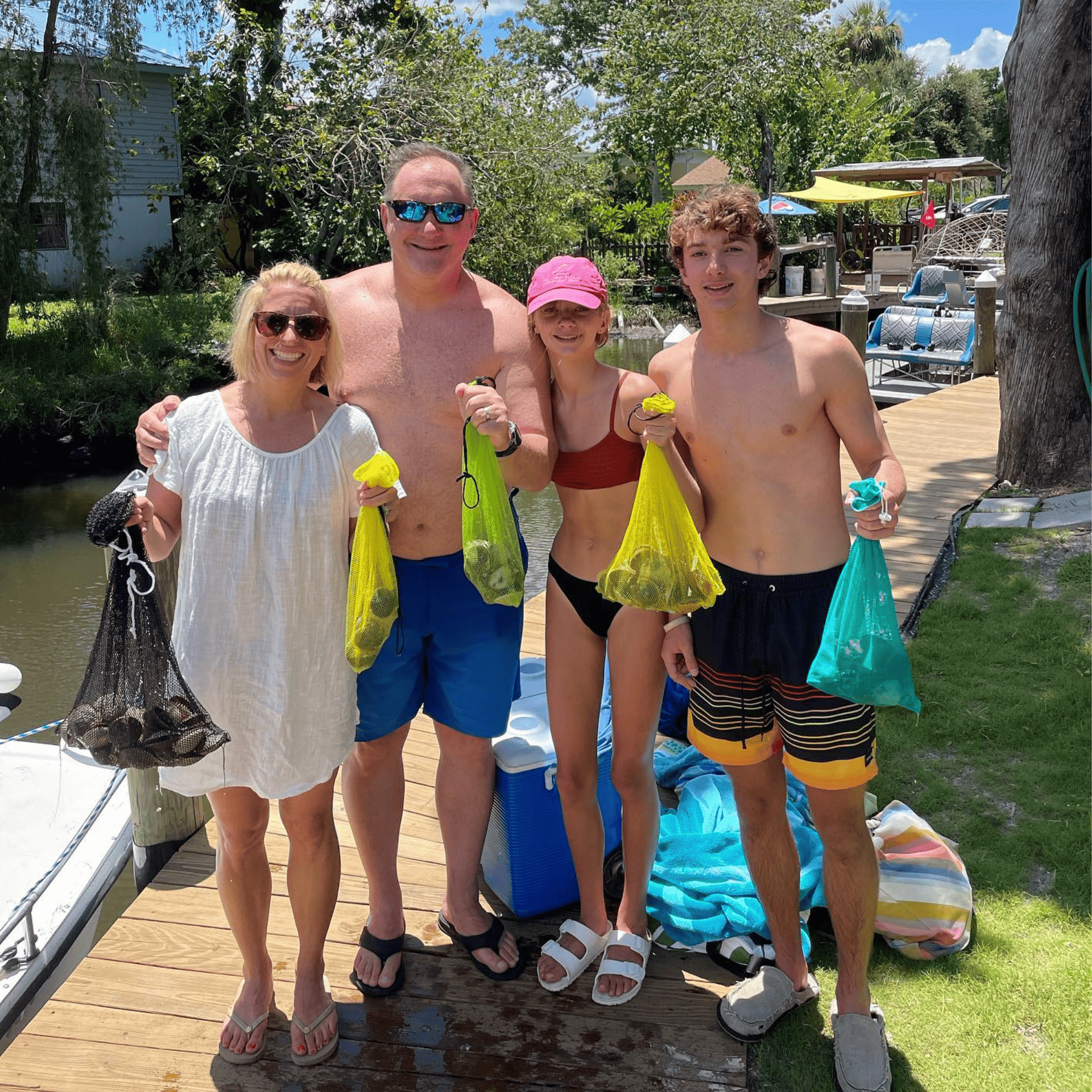 A group of people standing on a dock holding bags of scallops they caught