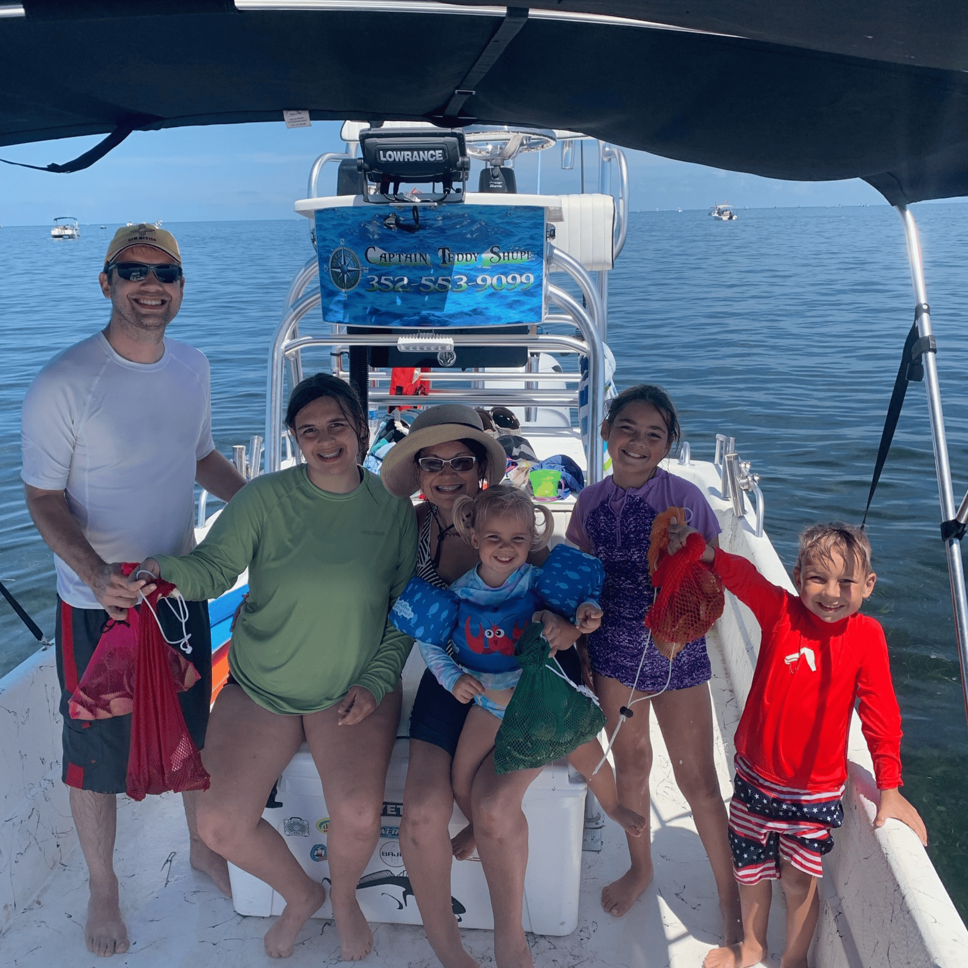 A group of people are posing for a picture on a boat in the ocean.