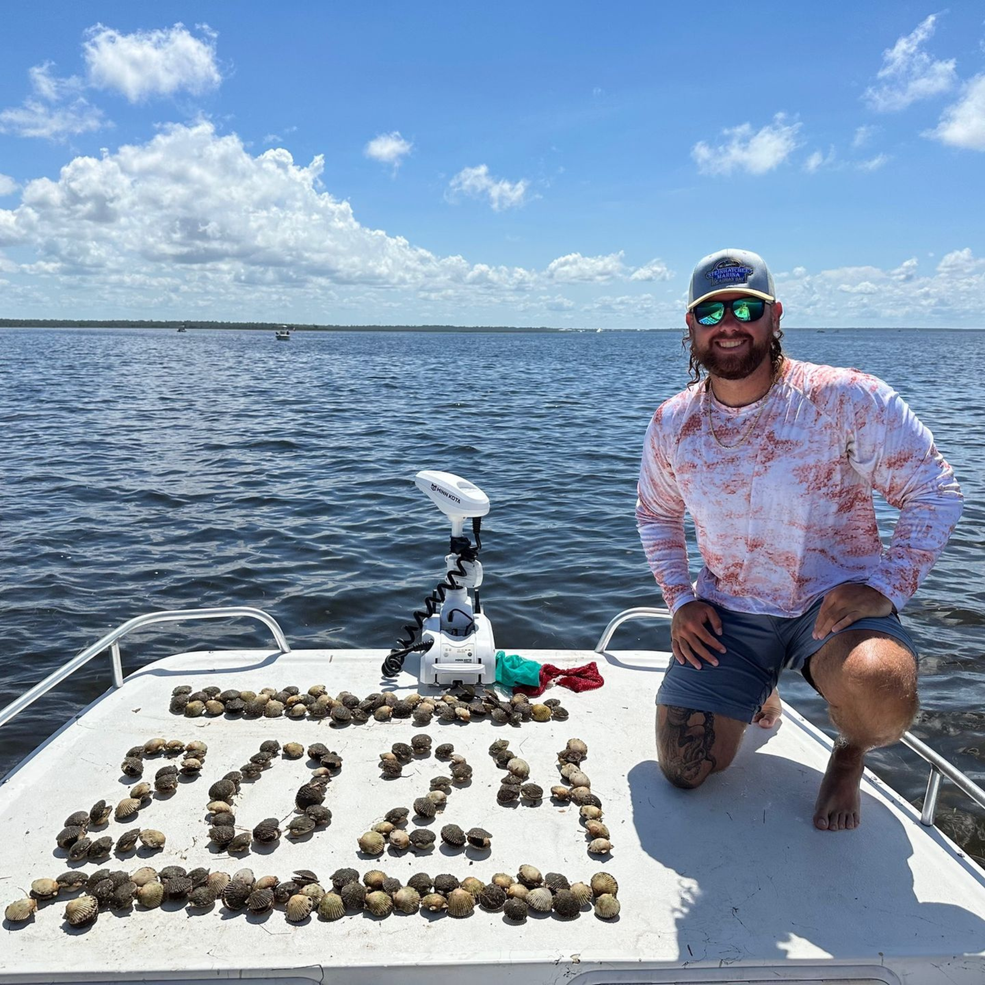 Captain Teddy Shupe kneeling on the deck of a boat with scallops.