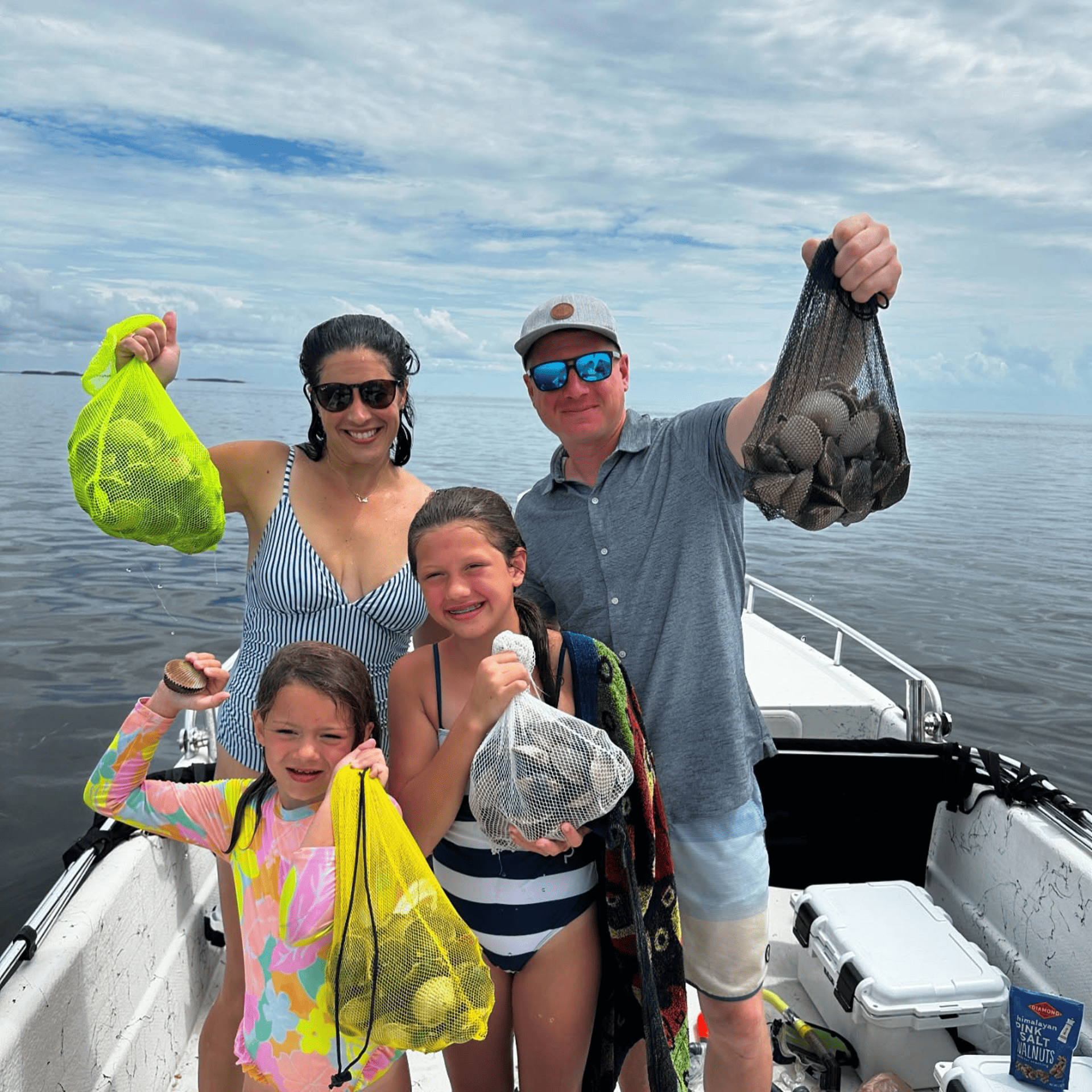 A family is standing on a boat holding bags of scallops