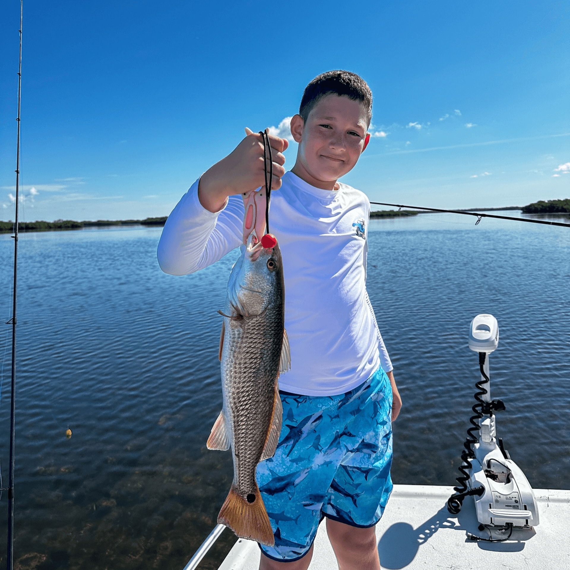 A young boy is holding a large fish on a boat
