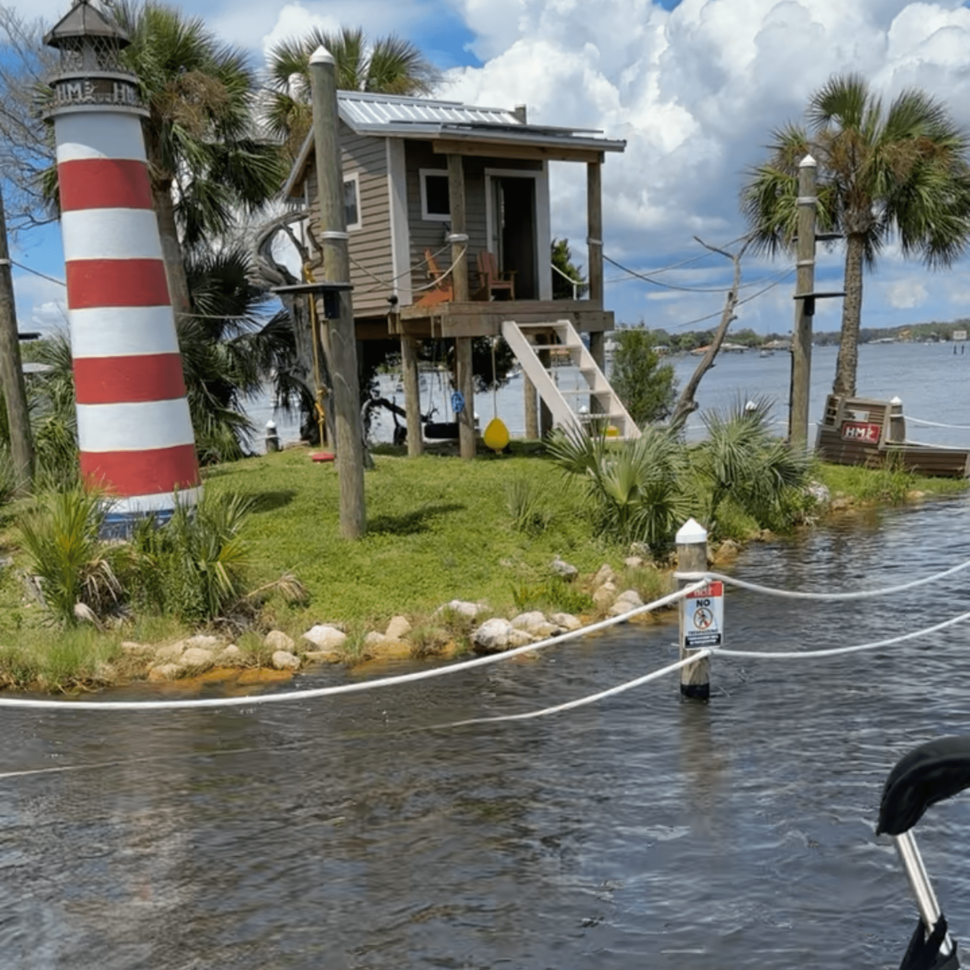 A house on stilts with a lighthouse in the background