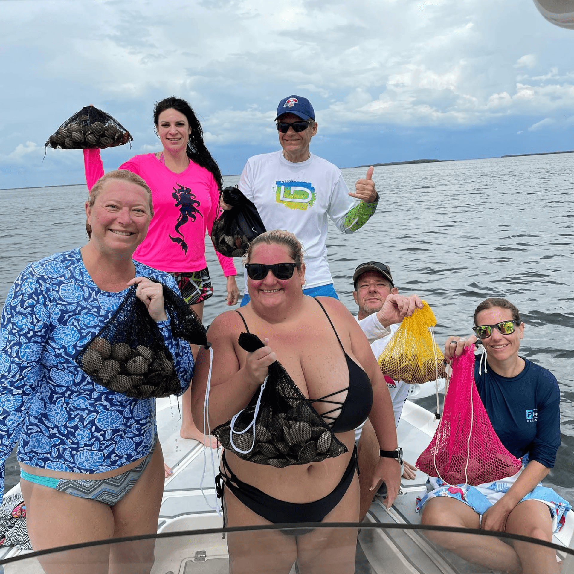 A group of people are posing for a picture on a boat with scallops in ozello