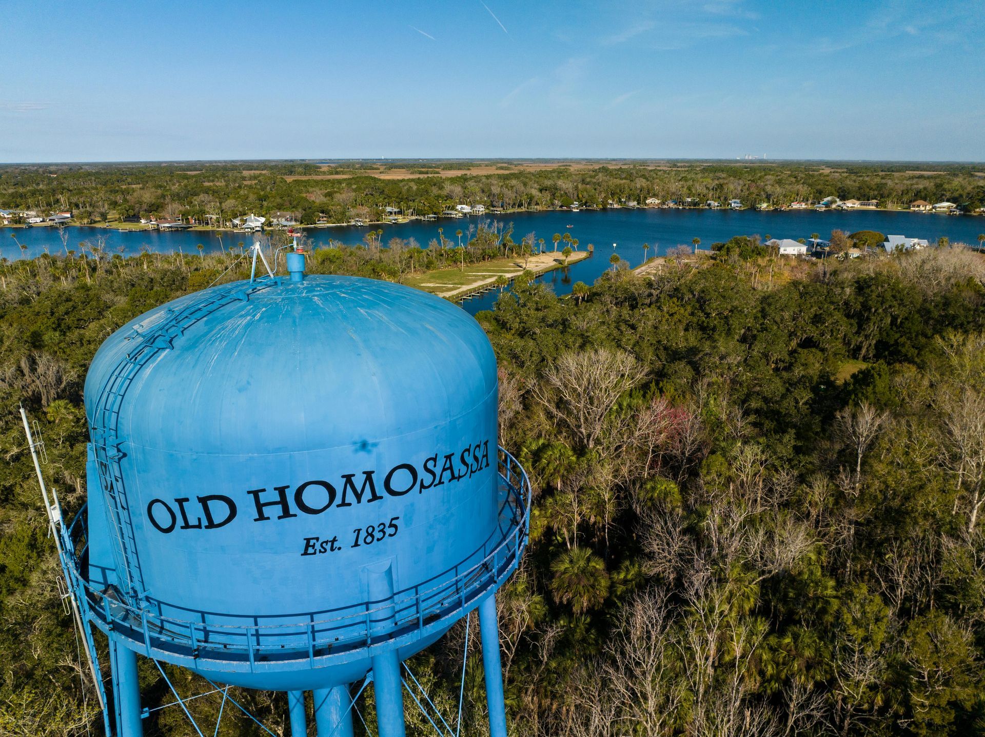 An aerial view of an old Homosassa water tower surrounded by trees and a river.