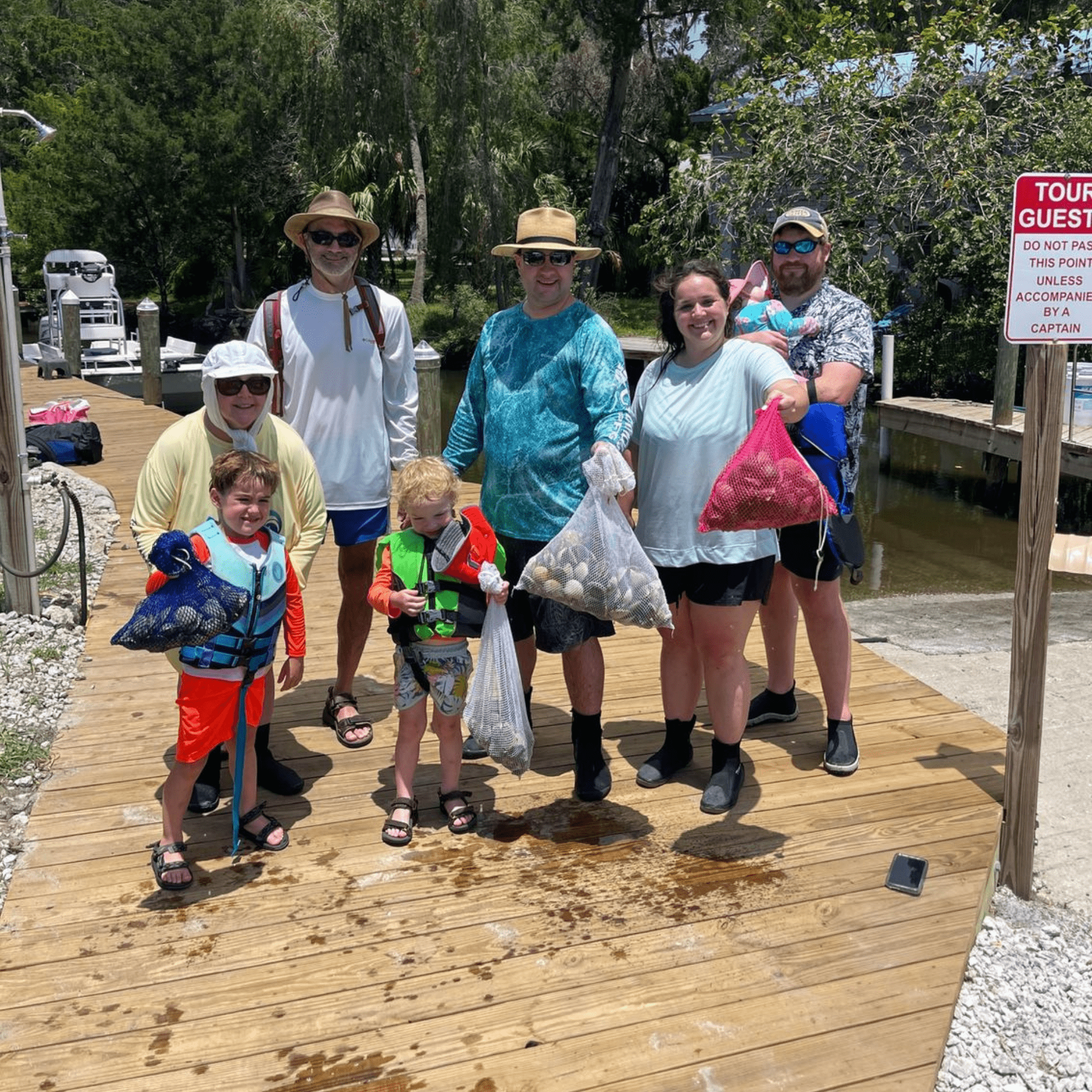 A group of people standing on a wooden deck holding bags of Scallops.