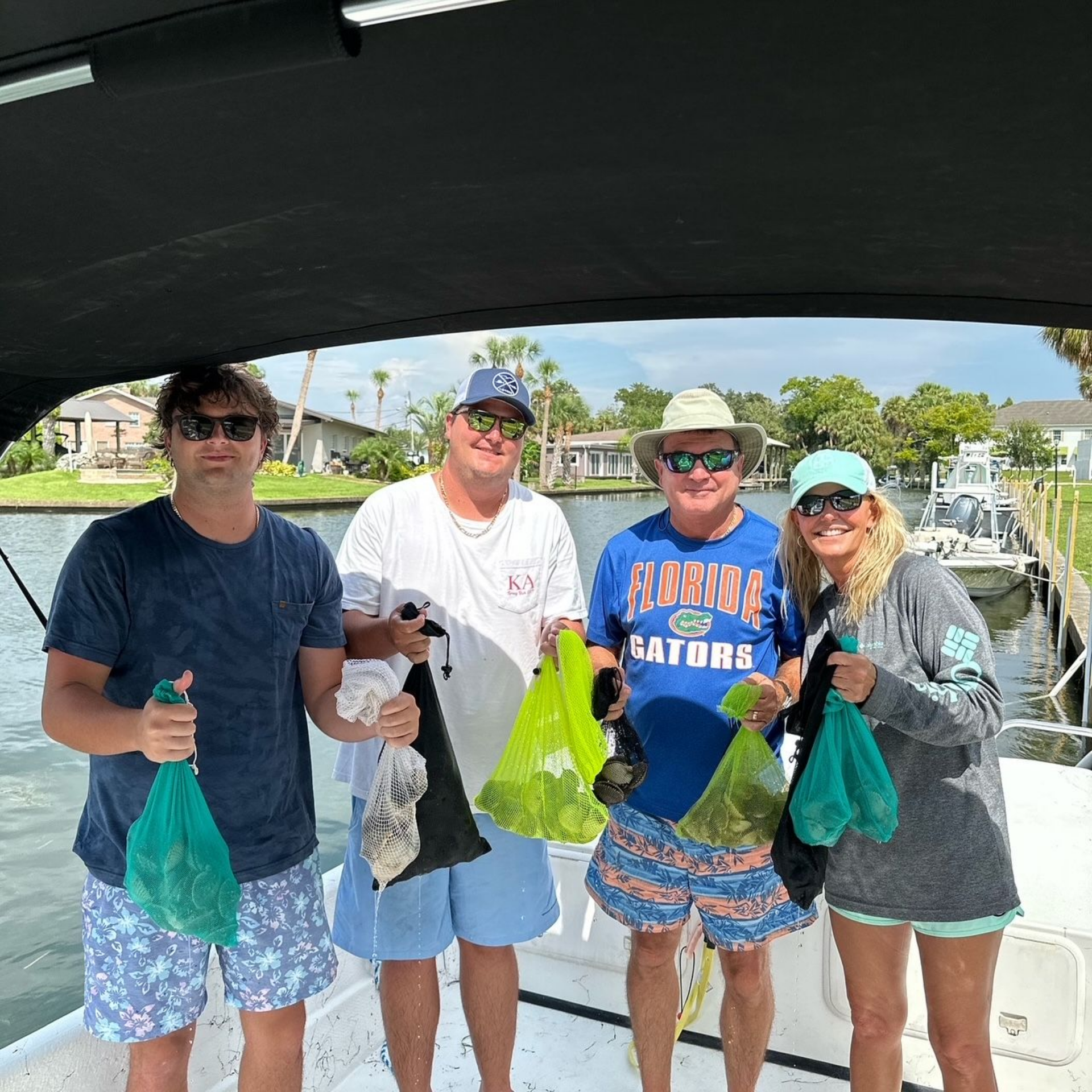 A group of people are standing on a boat holding bags of scallops in Steinhatchee