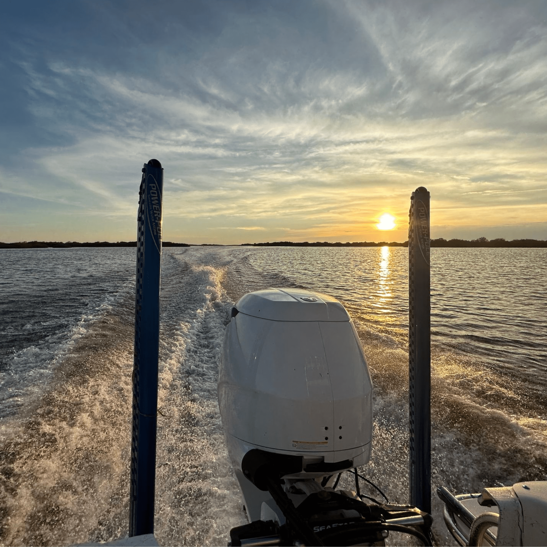 A boat is going through the water at sunset.