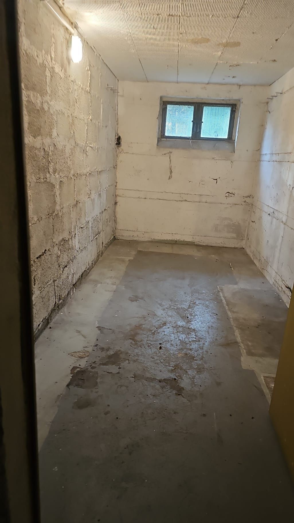 Kleiner, unfertiger Kellerraum mit Betonboden und Wänden aus Schlackenblöcken.