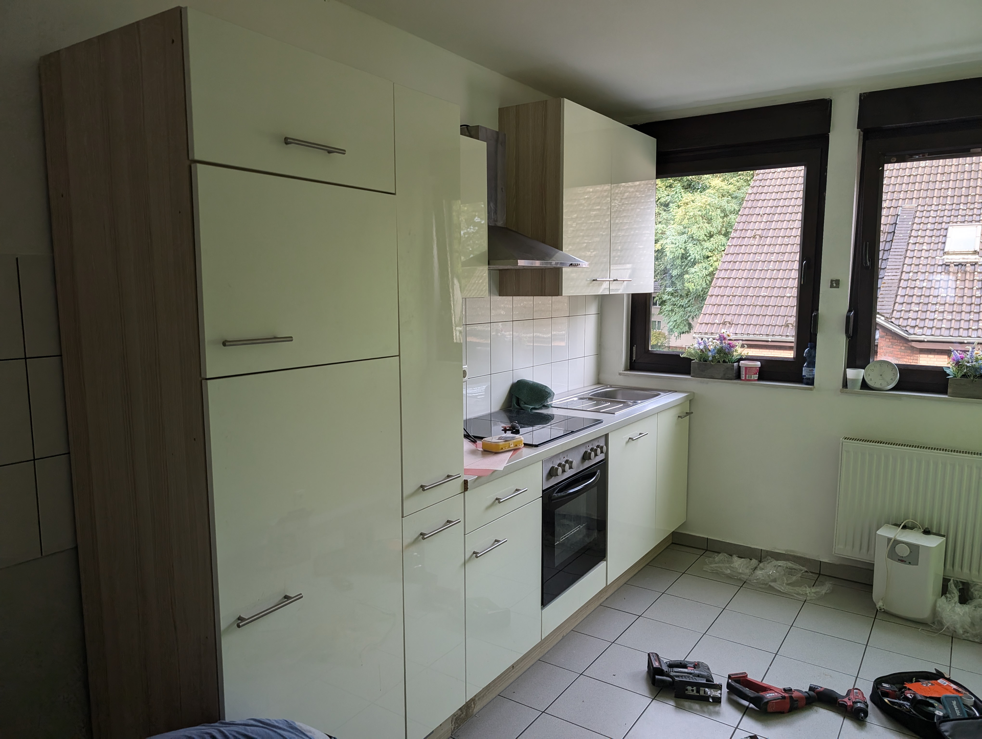 Küche mit weißen Schränken, Geräten aus Edelstahl und Speisekammer aus hellem Holz.